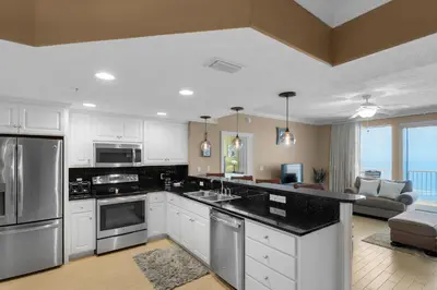 a kitchen with stainless steel appliances and a living room at Treasure Island 1910 in Panama City Beach