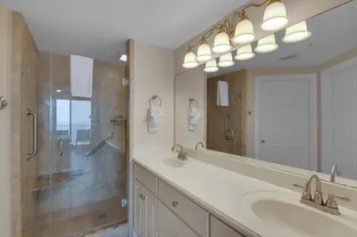 a bathroom with a sink and a shower and a mirror at Treasure Island 1611 in Panama City Beach