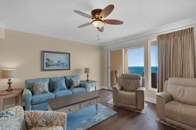 a living room with a blue couch and a ceiling fan at Treasure Island 1611 in Panama City Beach