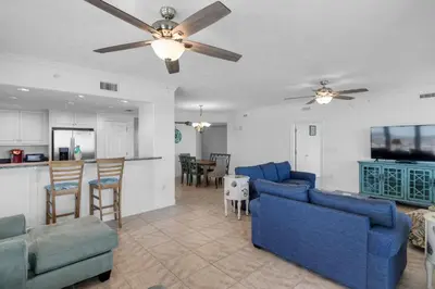 a living room with blue couches and a kitchen at Treasure Island 1612 in Panama City Beach