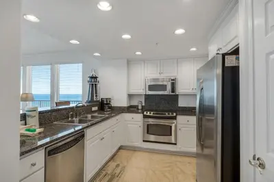a kitchen with white cabinets and stainless steel appliances at Treasure Island 1612 in Panama City Beach