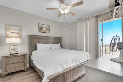 a bedroom with a bed with a ceiling fan and a window at Treasure Island 0801 in Panama City Beach
