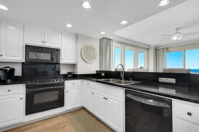 a kitchen with white cabinets and black appliances at Treasure Island 0801 in Panama City Beach