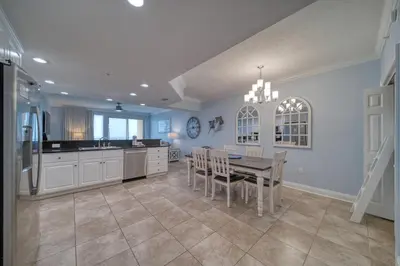 a dining room with a table and a kitchen at Treasure Island 1706 in Panama City Beach