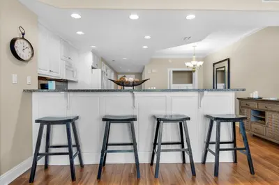 a kitchen with three bar stools in front of a counter at Treasure Island 1911 in Panama City Beach