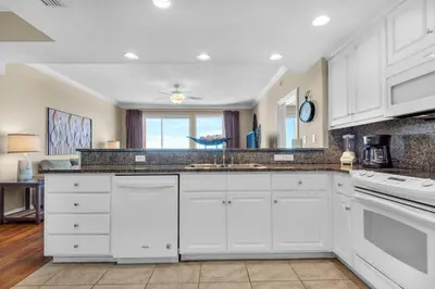 a kitchen with white cabinets and a large mirror at Treasure Island 1911 in Panama City Beach