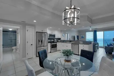 a kitchen and living room with a glass table and chairs at Treasure Island 0802 in Panama City Beach
