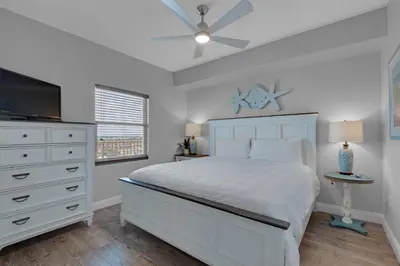 a bedroom with a bed and a dresser and a tv at Treasure Island 0802 in Panama City Beach