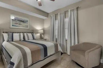 a bedroom with a bed and a chair and a window at Treasure Island 0805 in Panama City Beach