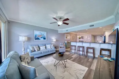 a living room with a blue couch and a kitchen at Treasure Island 1510 in Panama City Beach