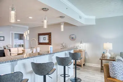 a kitchen with a counter and chairs in a room at Treasure Island 1811 in Panama City Beach