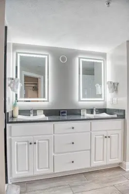 a bathroom with two sinks and two mirrors at Treasure Island 1811 in Panama City Beach