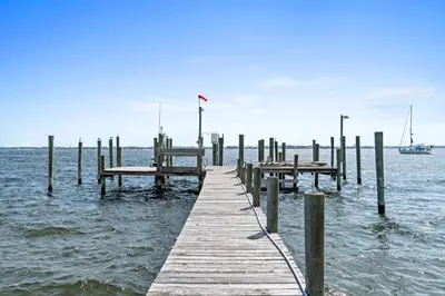 a wooden dock in the water with a boat at Spacious 3-Story Bayfront Home Perfect for Family Fun & Relaxation in Panama City