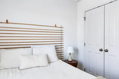 a bedroom with a white bed with a wooden headboard at Walk to Rosemary - Poolside, 6 Bikes, Beach Access in Inlet Beach