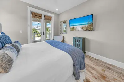 a bedroom with a bed and a tv on the wall at Town of Prominence- Just Beachy in Inlet Beach