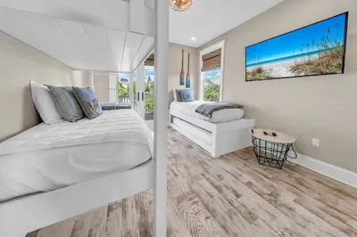 a white bedroom with a bed and a tv at Town of Prominence- Just Beachy in Inlet Beach