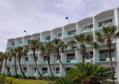 a large building with palm trees in front of it at Casa Loma Panama City Beach - Beachfront in Panama City Beach