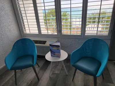 two blue chairs and a table in a room with a window at Casa Loma Panama City Beach - Beachfront in Panama City Beach