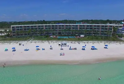 a beach with chairs and umbrellas in front of a hotel at Casa Loma Panama City Beach - Beachfront in Panama City Beach