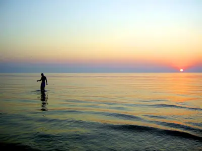 a person standing in the water at sunset at Casa Loma Panama City Beach - Beachfront in Panama City Beach