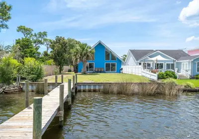 a house on the water with a dock at Dolphin Days Lagoon Retreat in Panama City Beach