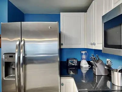 a kitchen with a stainless steel refrigerator and blue walls at Majestic Beach Towers I #2302 in Panama City Beach