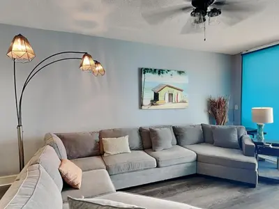 a living room with a gray couch and a lamp at Majestic Beach Towers I #2302 in Panama City Beach