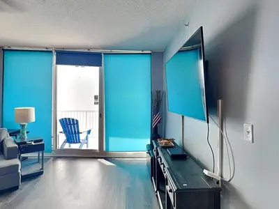 a living room with a tv and a chair at Majestic Beach Towers I #2302 in Panama City Beach