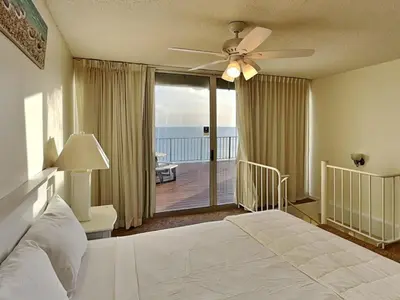 a bedroom with a bed with a ceiling fan and a balcony at Edgewater Tower III #1210 in Panama City Beach