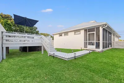 a backyard with a house and an umbrella at Charming 3/2 Beach House w/ POOL & Golf Cart INCLUDED - 1 Min Walk to Beach in Panama City Beach