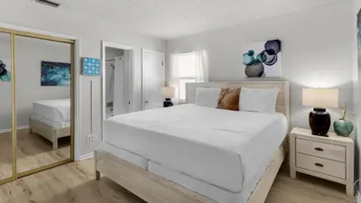 a bedroom with a large white bed and a mirror at Eastern Shores 215 in Santa Rosa Beach