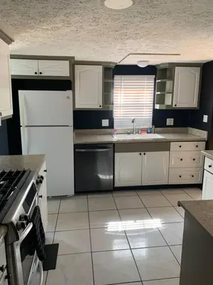 a kitchen with white cabinets and a white refrigerator at Double Wide Getaway in PCB in Panama City Beach