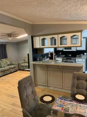 a living room with two chairs and a kitchen at Double Wide Getaway in PCB in Panama City Beach