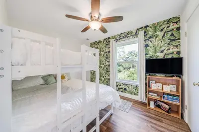 a bedroom with white bunk beds and a ceiling fan at Dolphin's Den in Panama City Beach