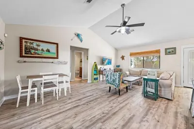 a living room with a ceiling fan and a table at Beachcombers Nook, Firepit, yard, Sleeps 8, Walk to Beach in Panama City Beach