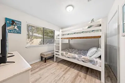 a bedroom with two bunk beds and a desk at Beachcombers Nook, Firepit, yard, Sleeps 8, Walk to Beach in Panama City Beach