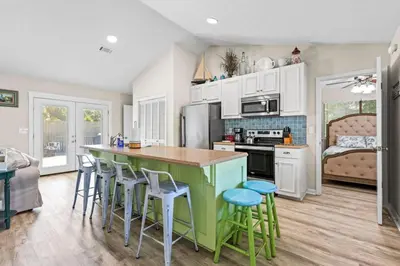 a kitchen with a green island and bar stools at Beachcombers Nook, Firepit, yard, Sleeps 8, Walk to Beach in Panama City Beach