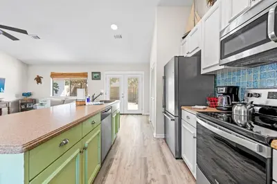 a kitchen with white cabinets and a counter top at Beachcombers Nook, Firepit, yard, Sleeps 8, Walk to Beach in Panama City Beach