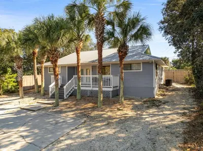 a house with palm trees in front of it at Beachcombers Nook, Firepit, yard, Sleeps 8, Walk to Beach in Panama City Beach