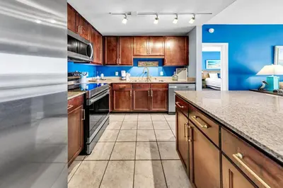a kitchen with wooden cabinets and blue walls at Laketown Wharf 927 in Panama City Beach