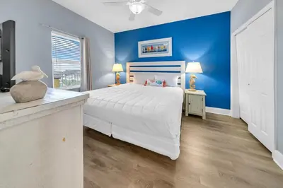 a bedroom with a white bed and a blue wall at Laketown Wharf 927 in Panama City Beach