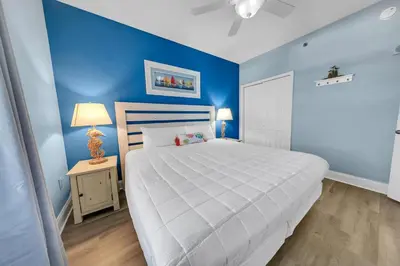 a bedroom with a large white bed and blue walls at Laketown Wharf 927 in Panama City Beach
