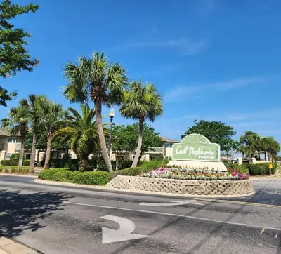 a sign for a hotel on a street with palm trees at Gulf Highlands Beach Townhouse in Panama City Beach