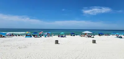 a group of people sitting on a beach with umbrellas at Gulf Highlands Beach Townhouse in Panama City Beach