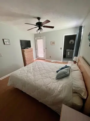 a bedroom with a large bed with a ceiling fan at Cozy Two-Bedroom Cottage-5min walk to beach! in Panama City Beach