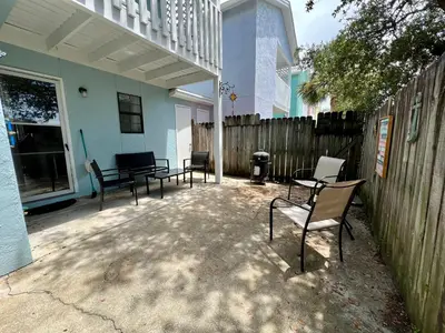 a patio with chairs and a fence in front of a house at Cozy Two-Bedroom Cottage-5min walk to beach! in Panama City Beach