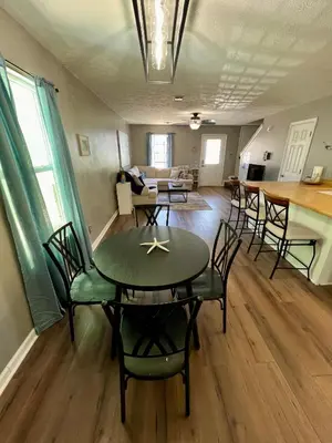 a dining room and living room with a table and chairs at Cozy Two-Bedroom Cottage-5min walk to beach! in Panama City Beach