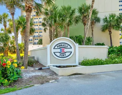 a sign in front of a building with palm trees at Pinnacle Port A-305 in Panama City Beach