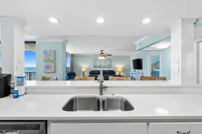 a kitchen with a sink and a living room at Pelican Walk 1012 in Panama City Beach