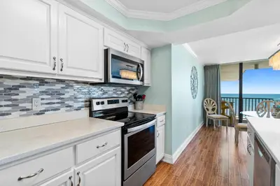 a kitchen with white cabinets and a view of the ocean at Pelican Walk 1012 in Panama City Beach